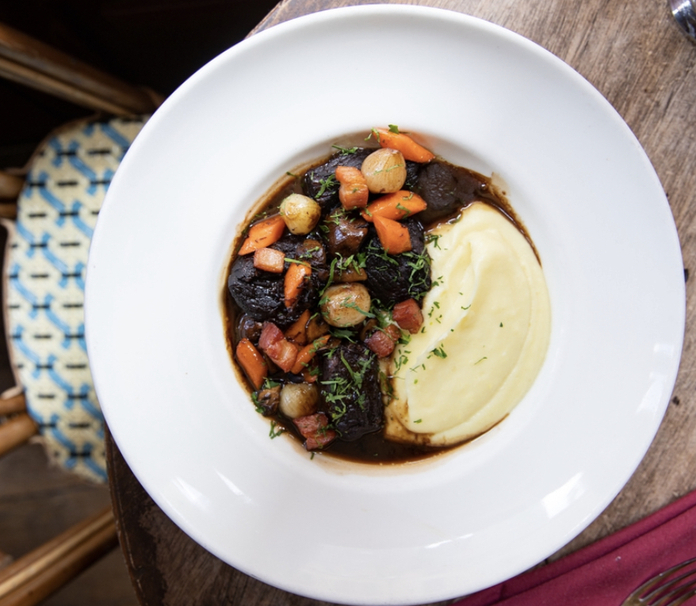 Hearty stew with vegetables and mashed potatoes served on a white plate.